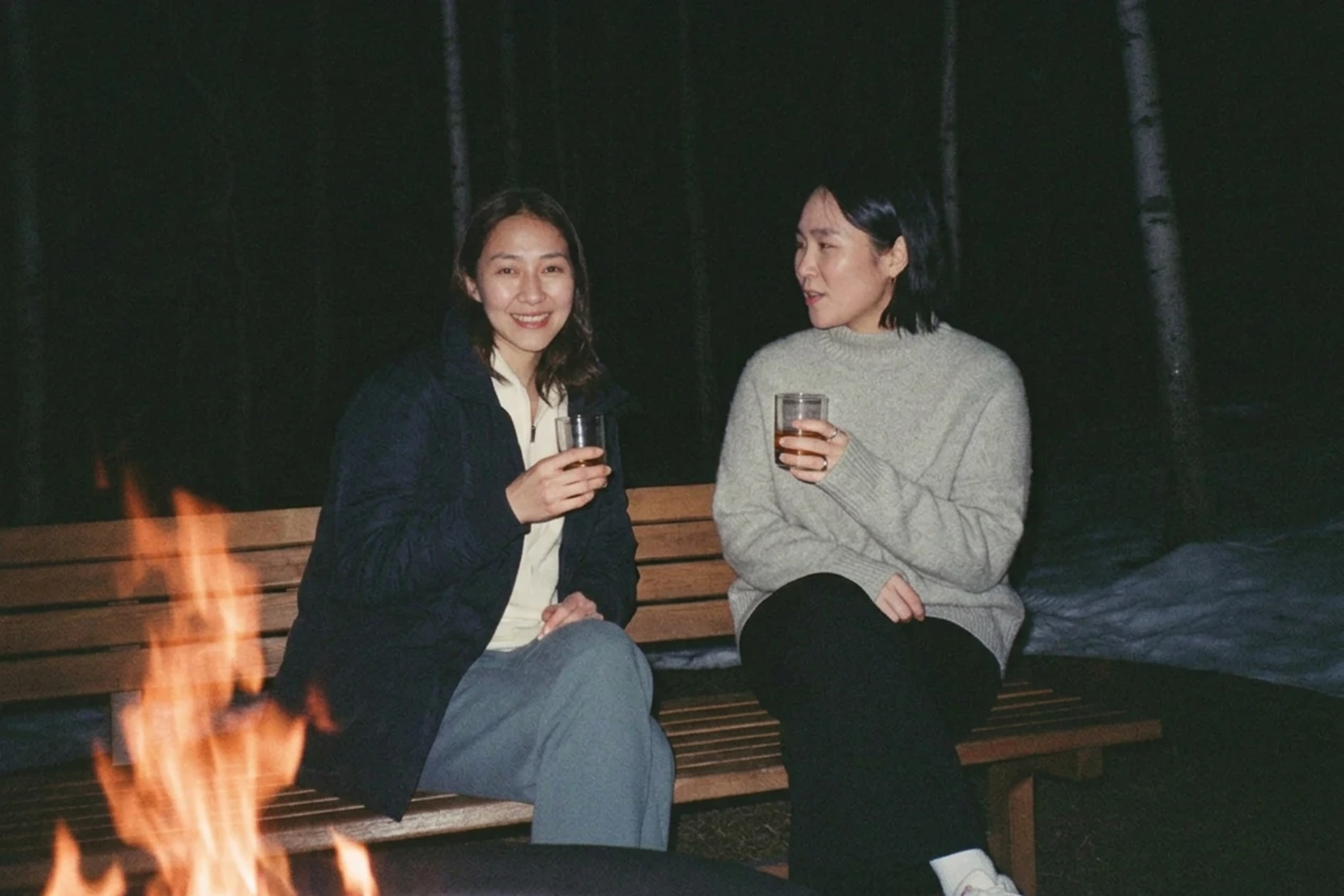 焚き火のそばでお酒を楽しむ大人