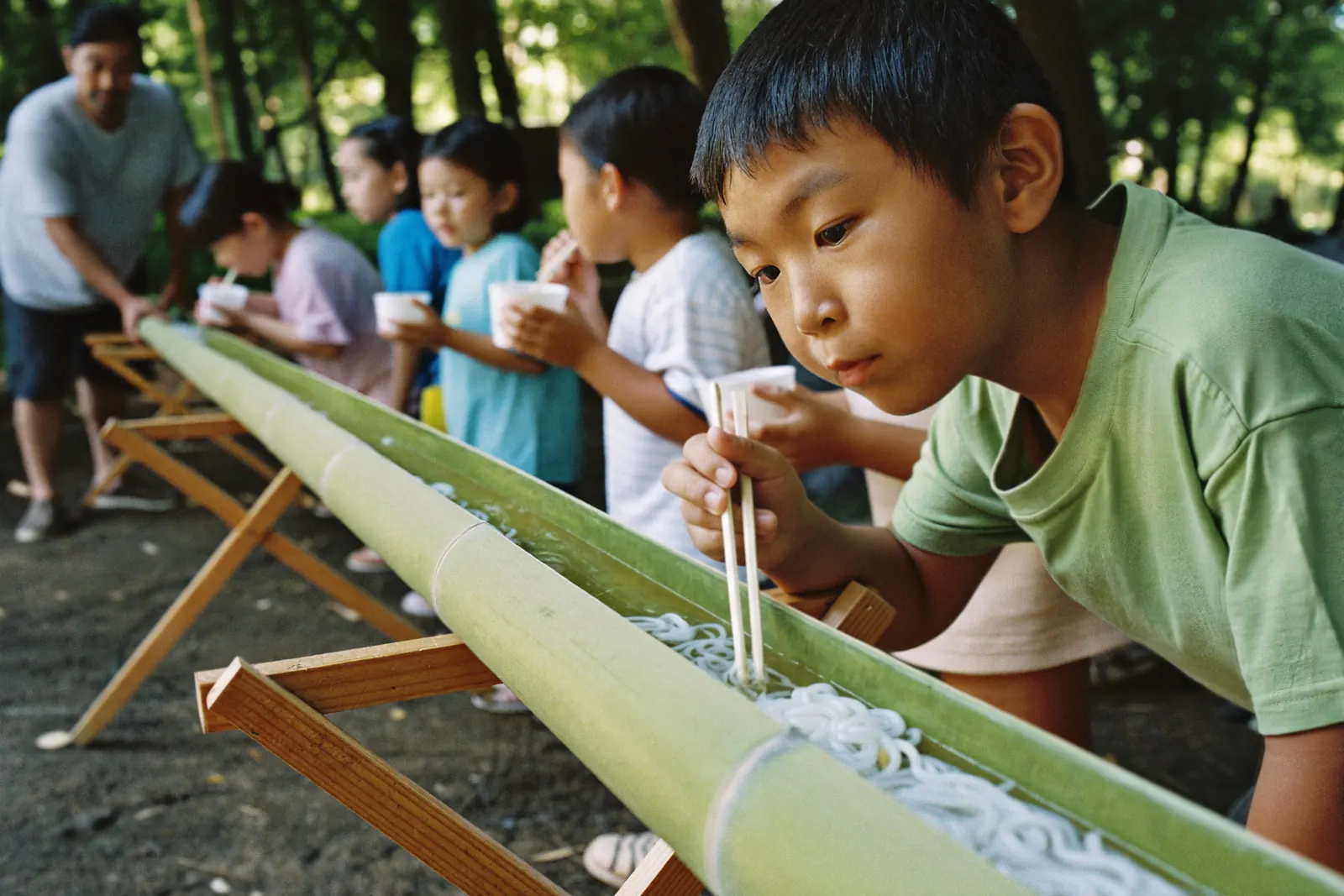 竹のコースに並んでそうめんを待つ子どもたち