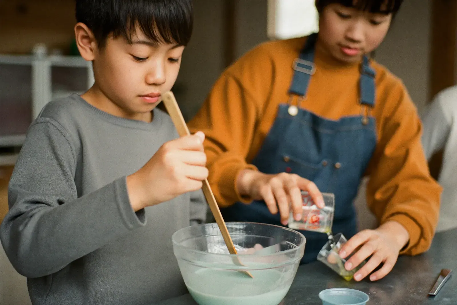 材料を混ぜてスライムを作る子どもとクルー