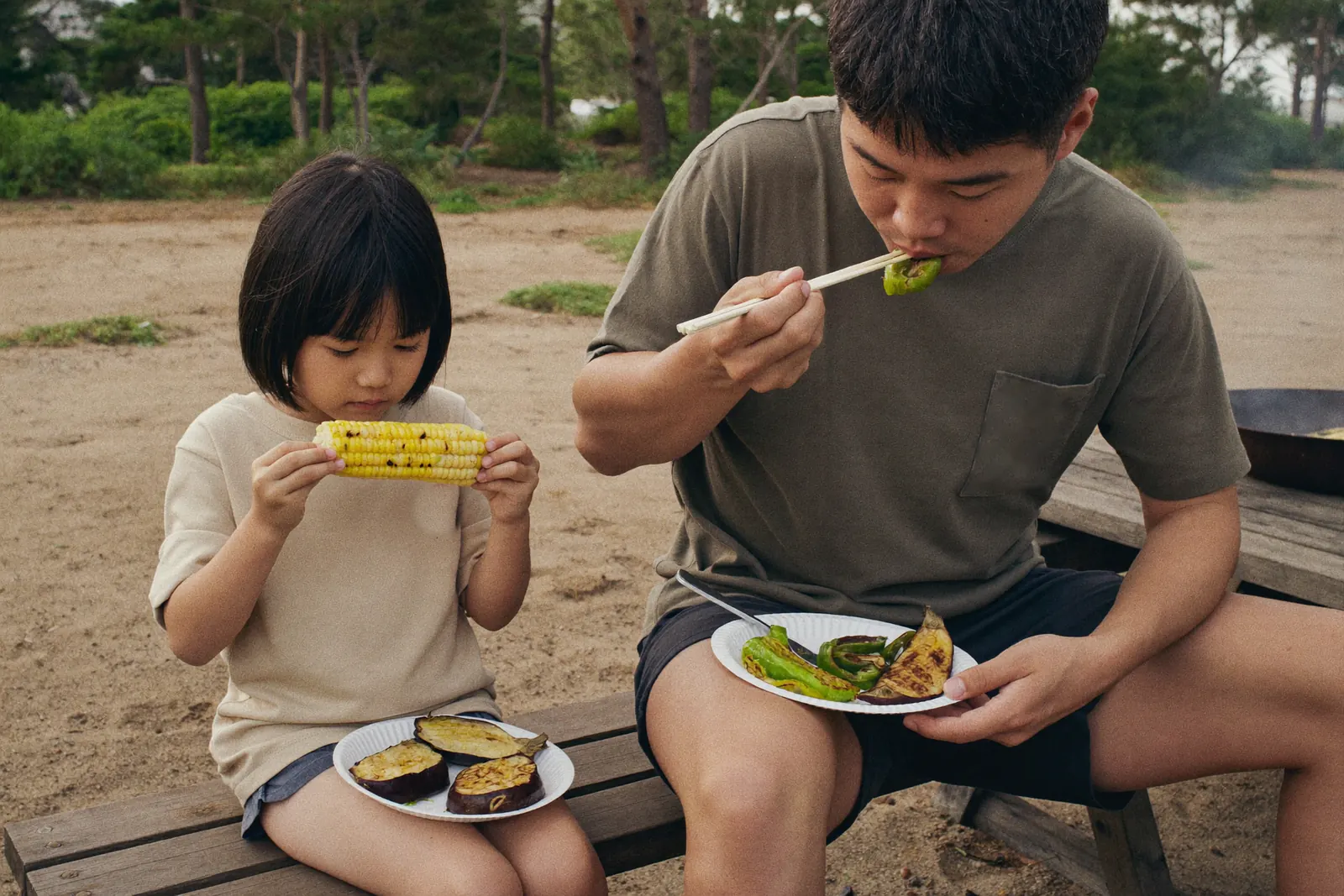 焼きとうもろこしを食べる女の子と父親