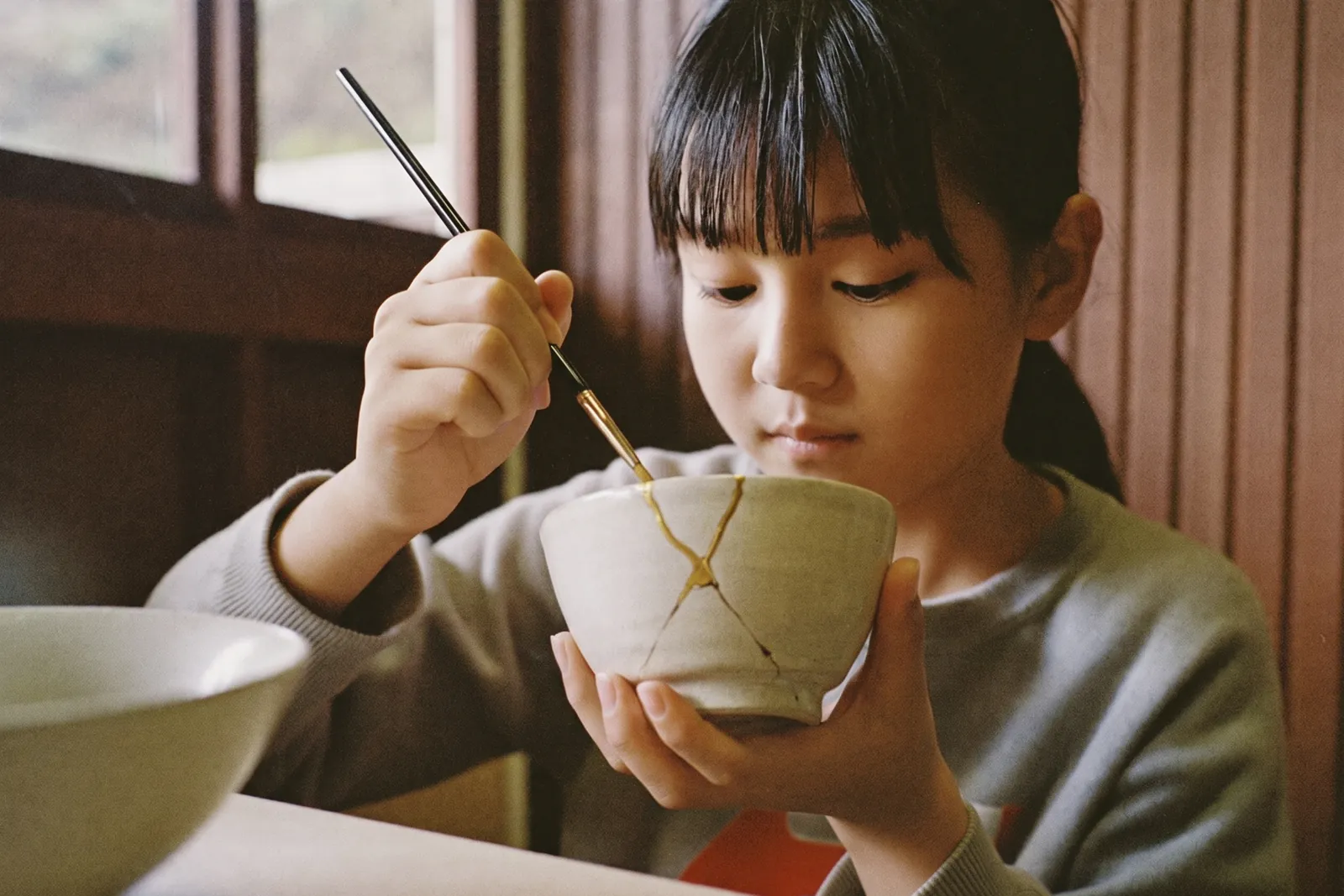 器のひびを金でなぞる女の子