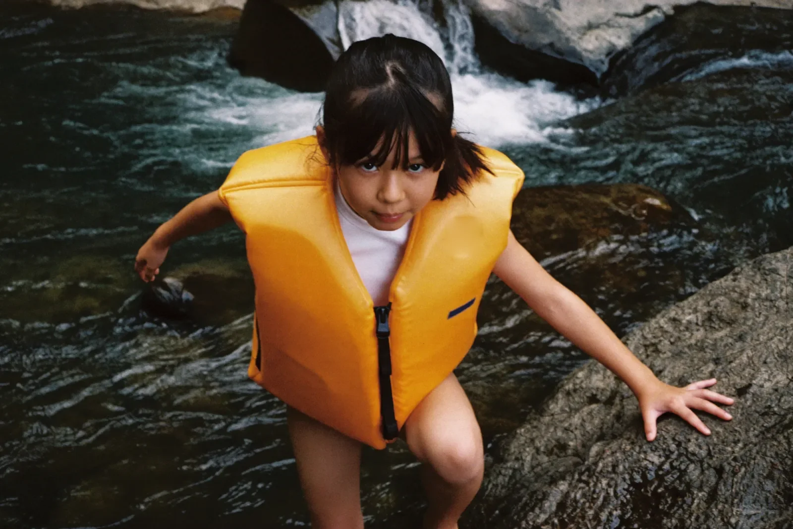 ライフジャケットで岩をこえる女の子