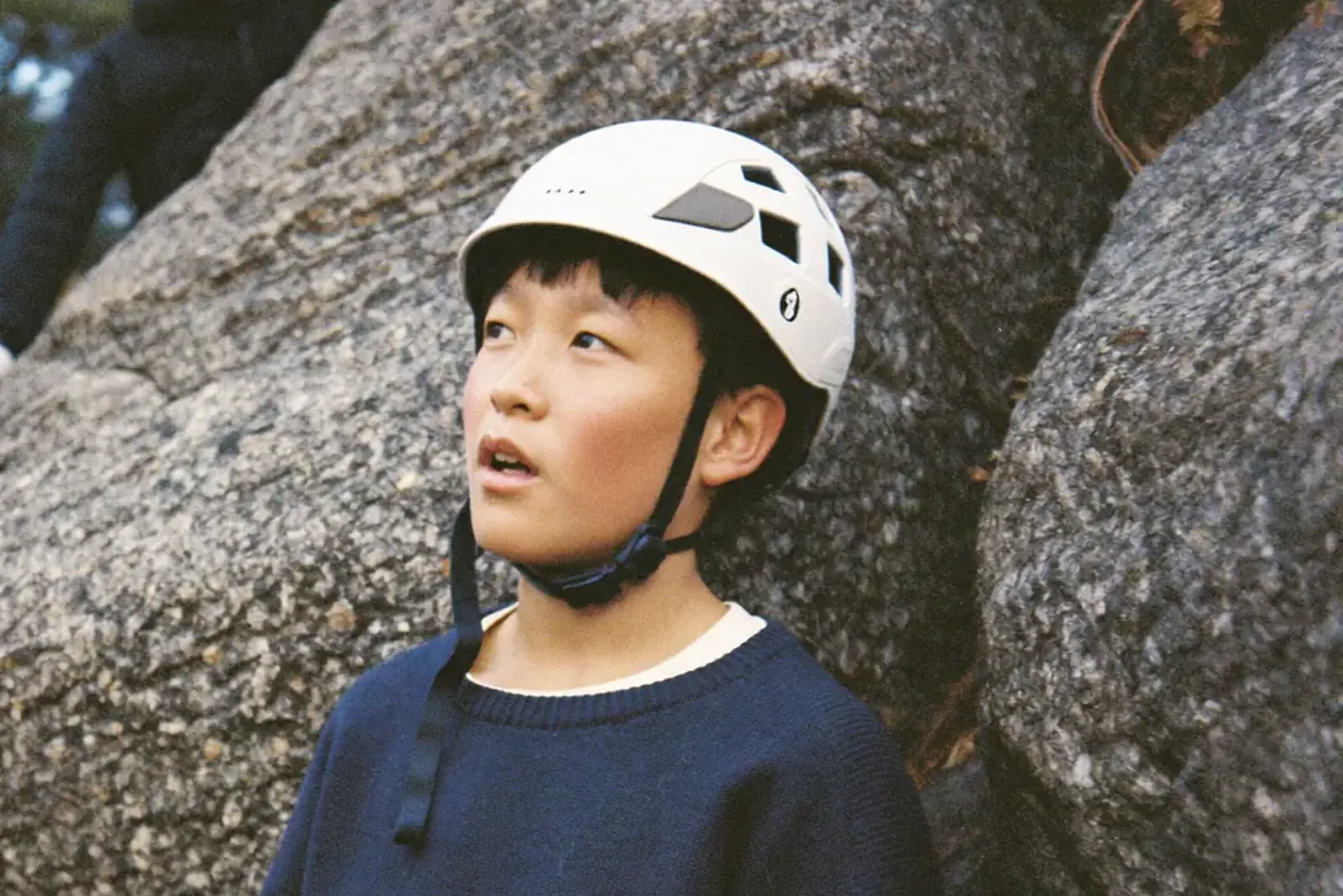 ヘルメットをかぶって岩を見上げる男の子