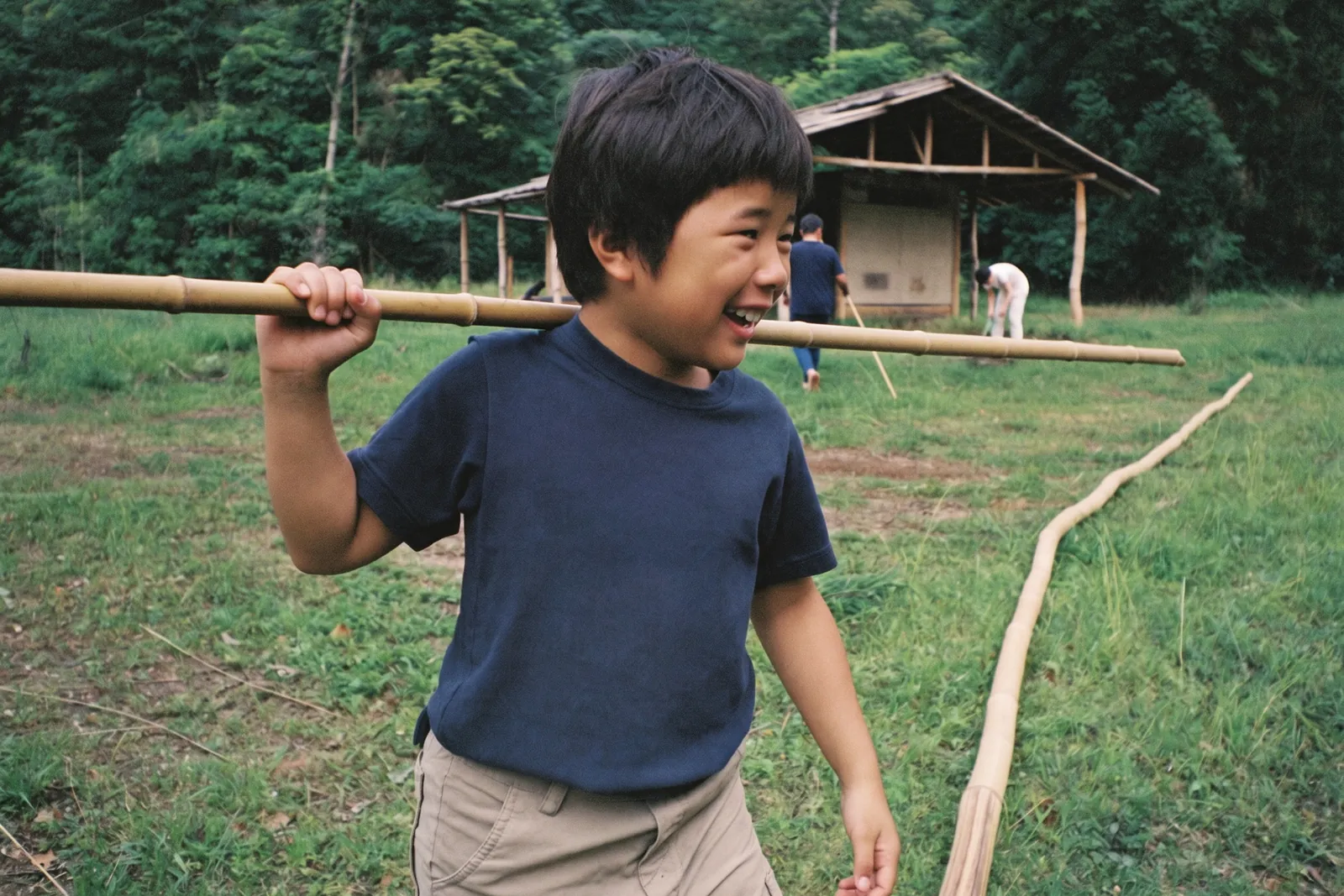 竹の棒をかついで笑う男の子