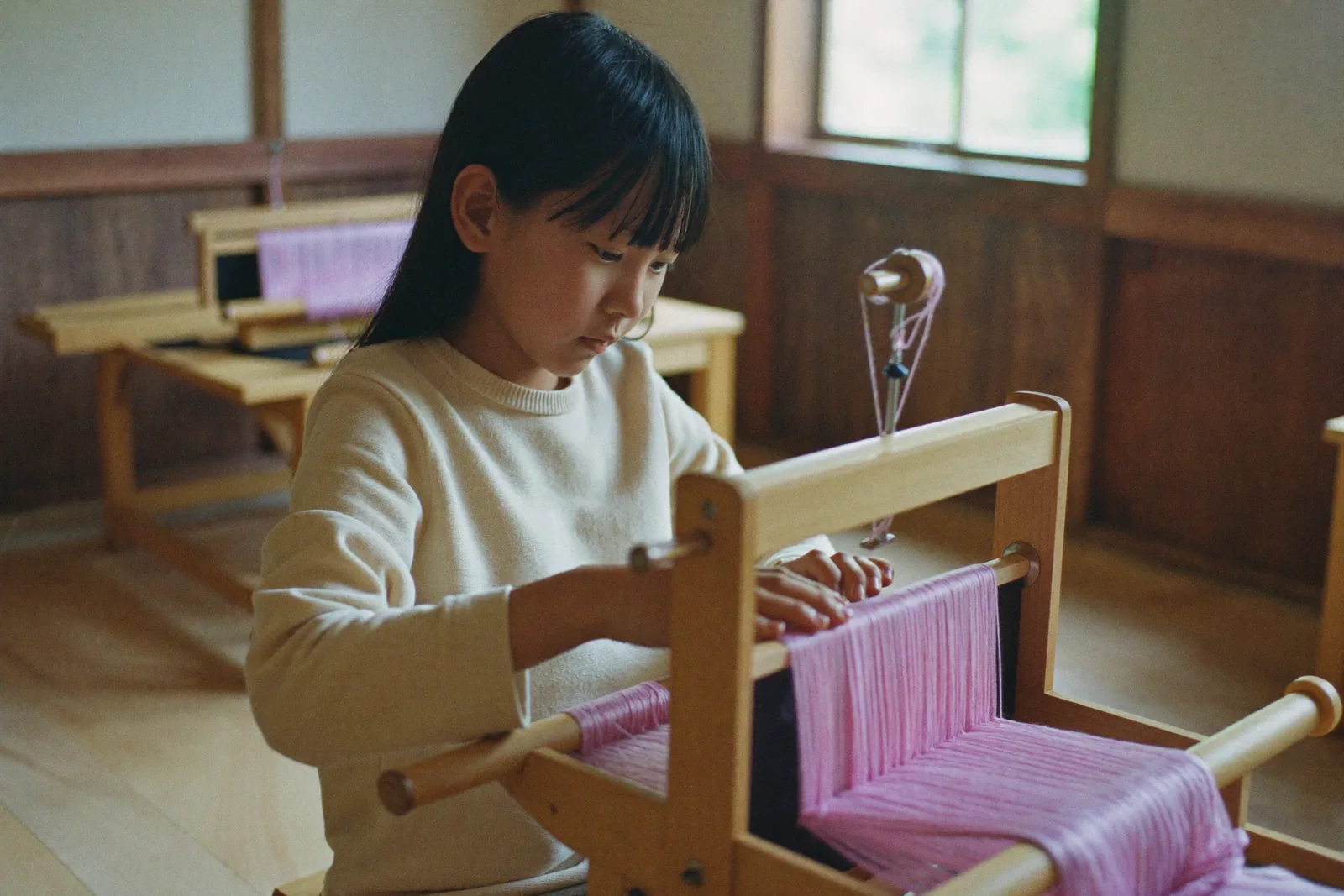 織り機で絹糸を織る女の子