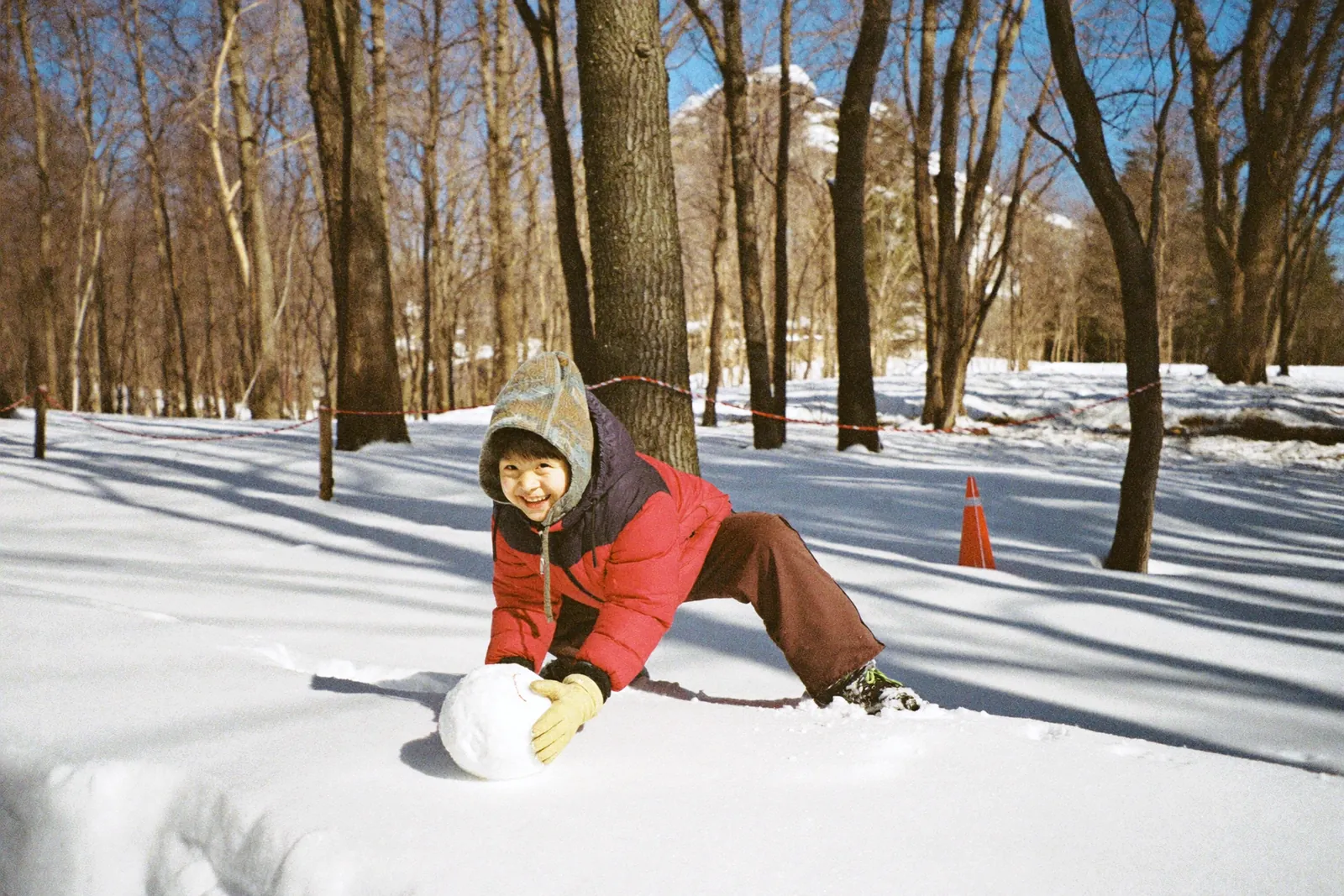 雪玉をころがして笑う男の子