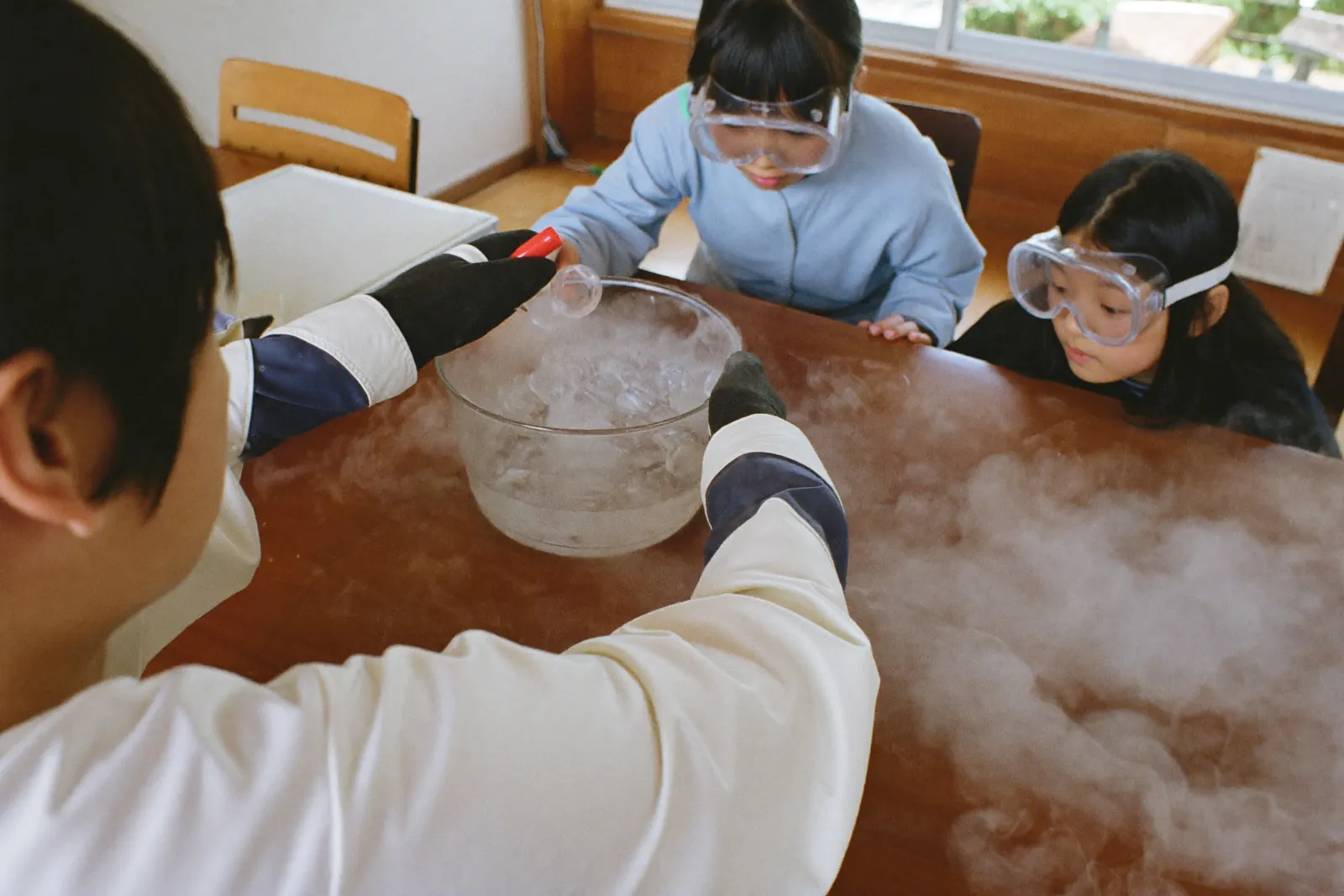 ドライアイスの白い煙をのぞきこむ子どもたち