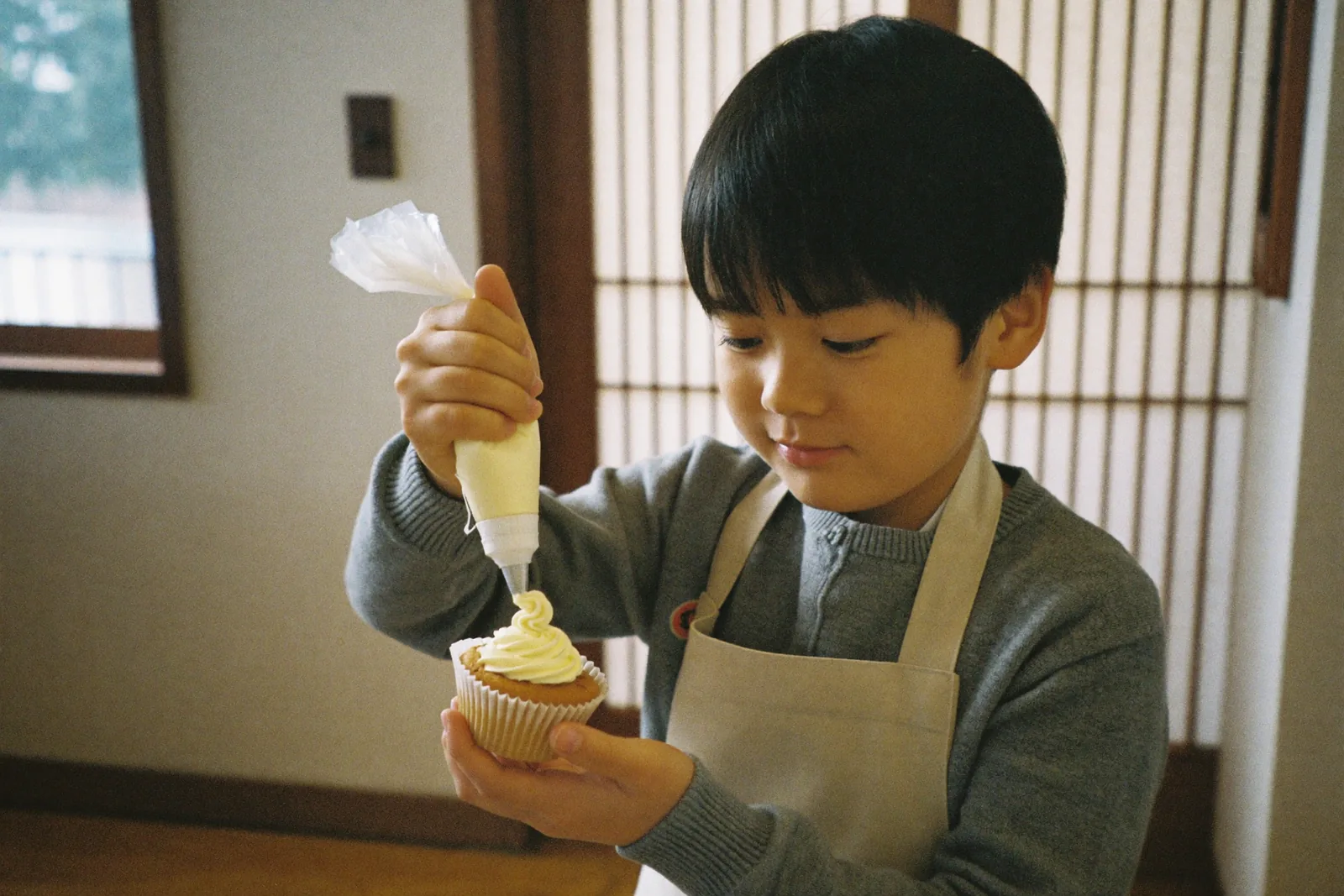 カップケーキにクリームを絞る男の子