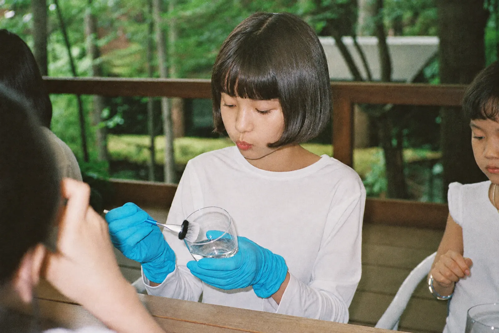 手袋をしてグラスの指紋を調べる女の子