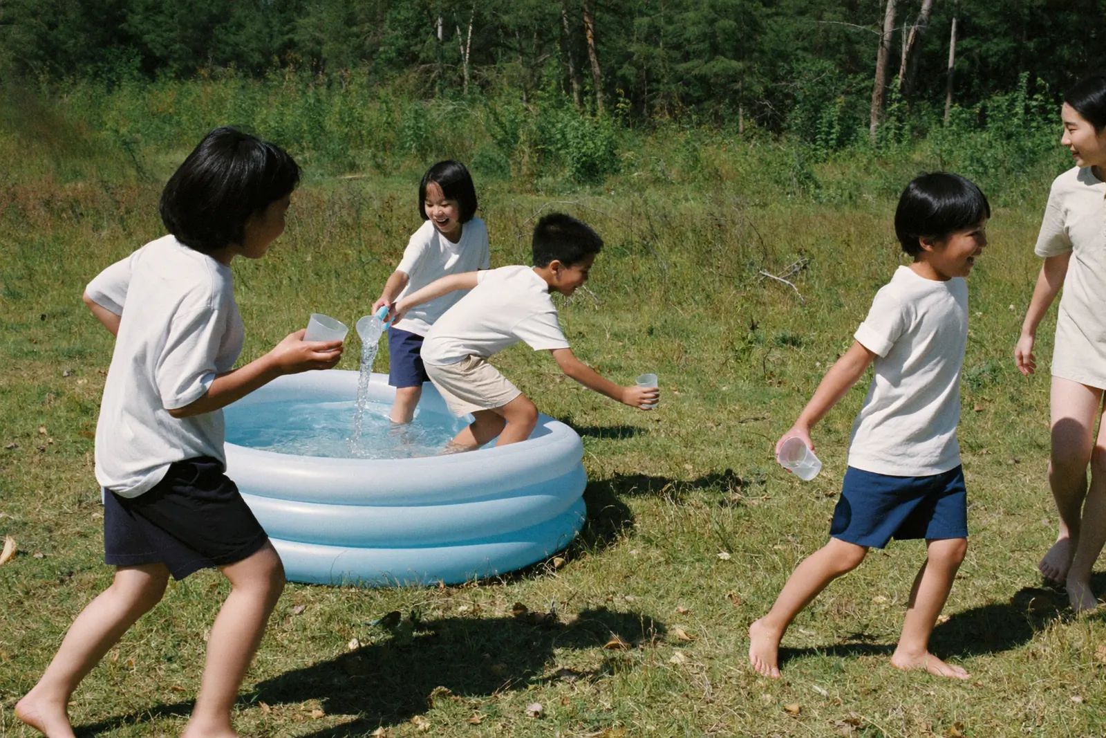 プールの水をカップで運ぶ子どもたち