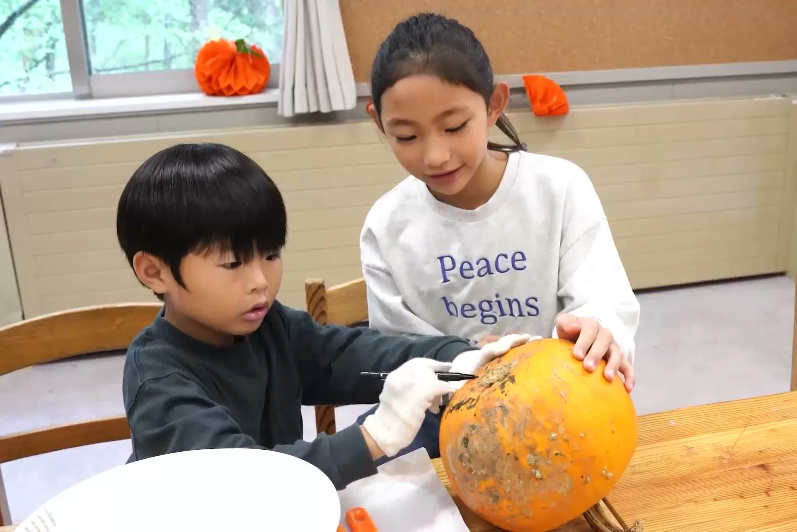 オレンジ色のかぼちゃを彫る男の子と女の子