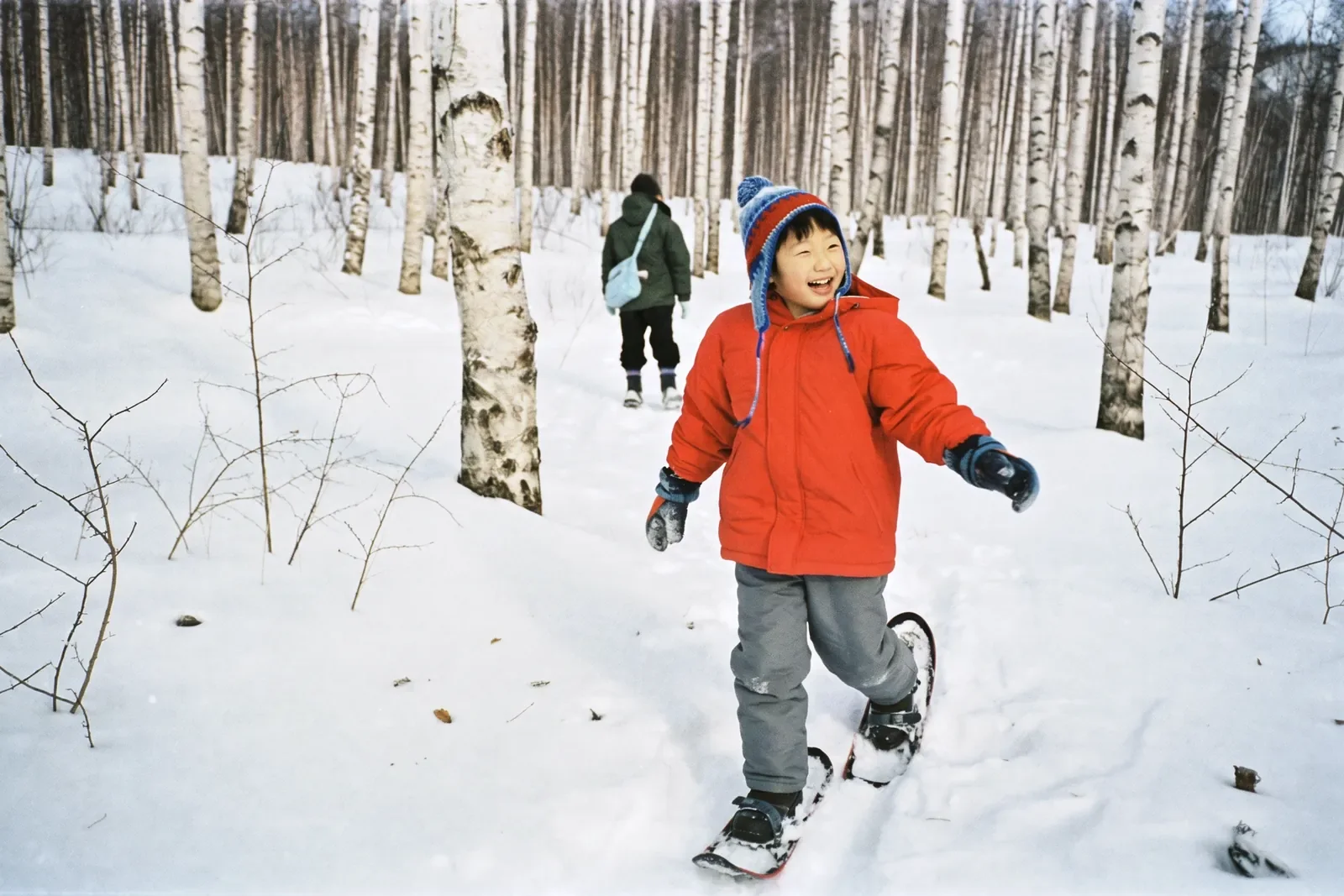 スノーシューで雪の森を歩く男の子