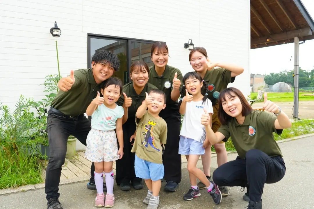 笑顔で親指を立てるクルーと子どもたち
