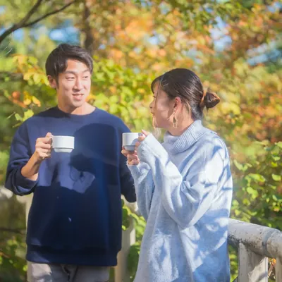 森のテラスで、カップを手に話す大人ふたり